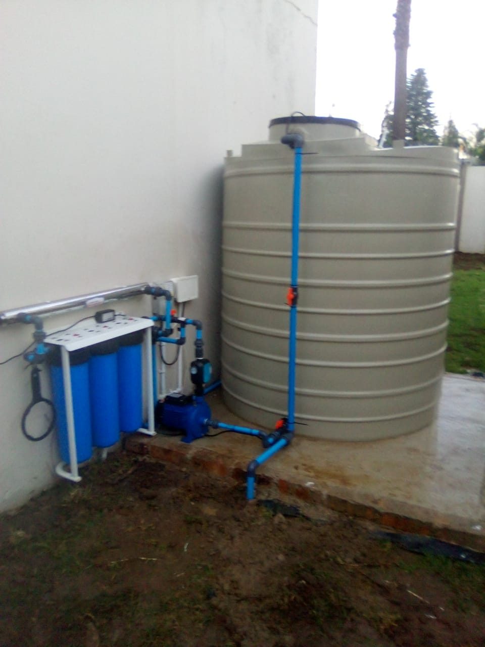Water tank with pump and UV filtration system installed against a wall